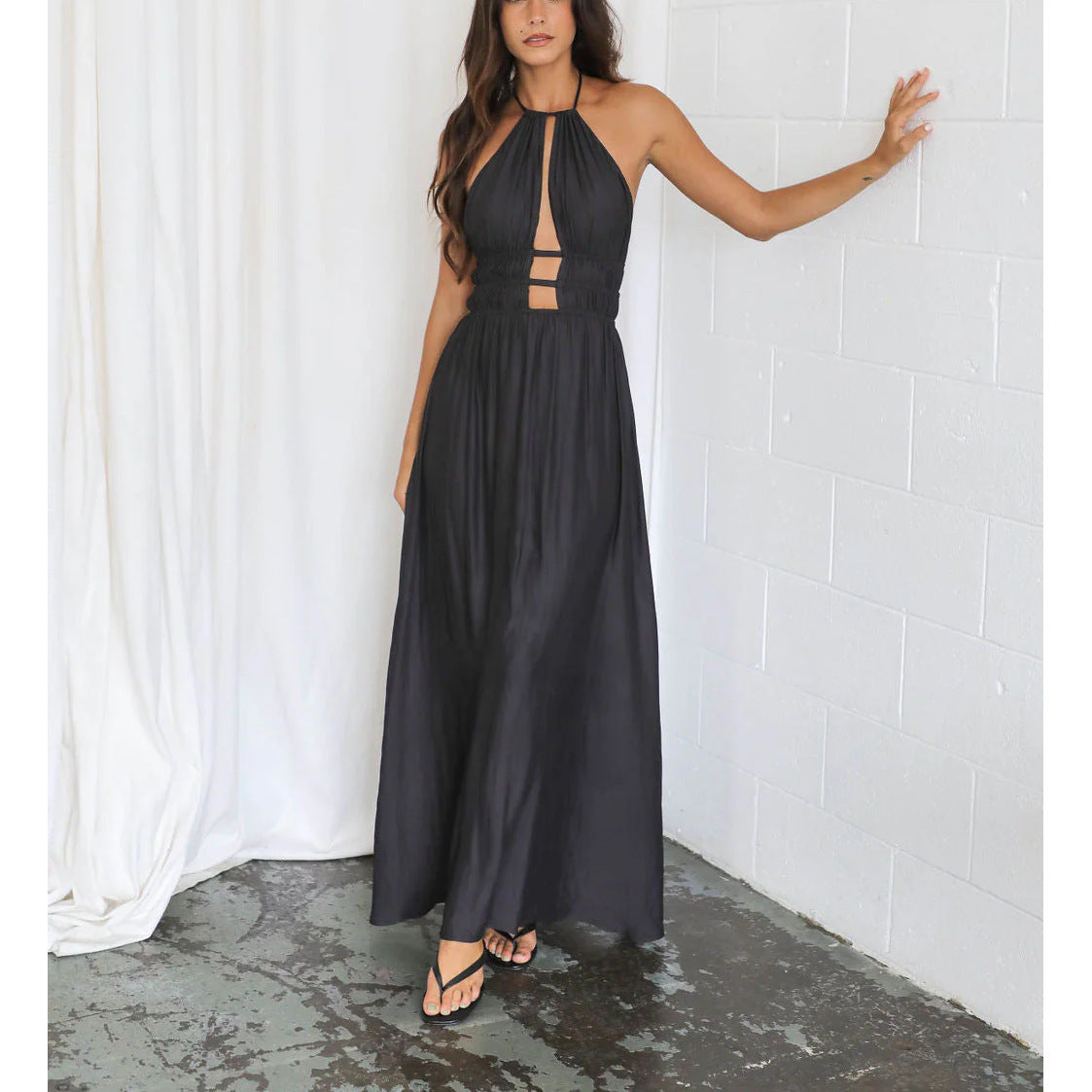 Black halter maxi dress with cut-out details on a white background room.