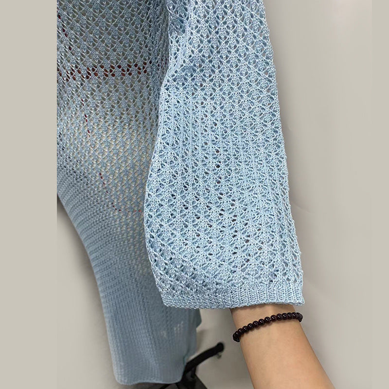 Close-up of a light blue crochet knit sleeve of a dress on a neutral background