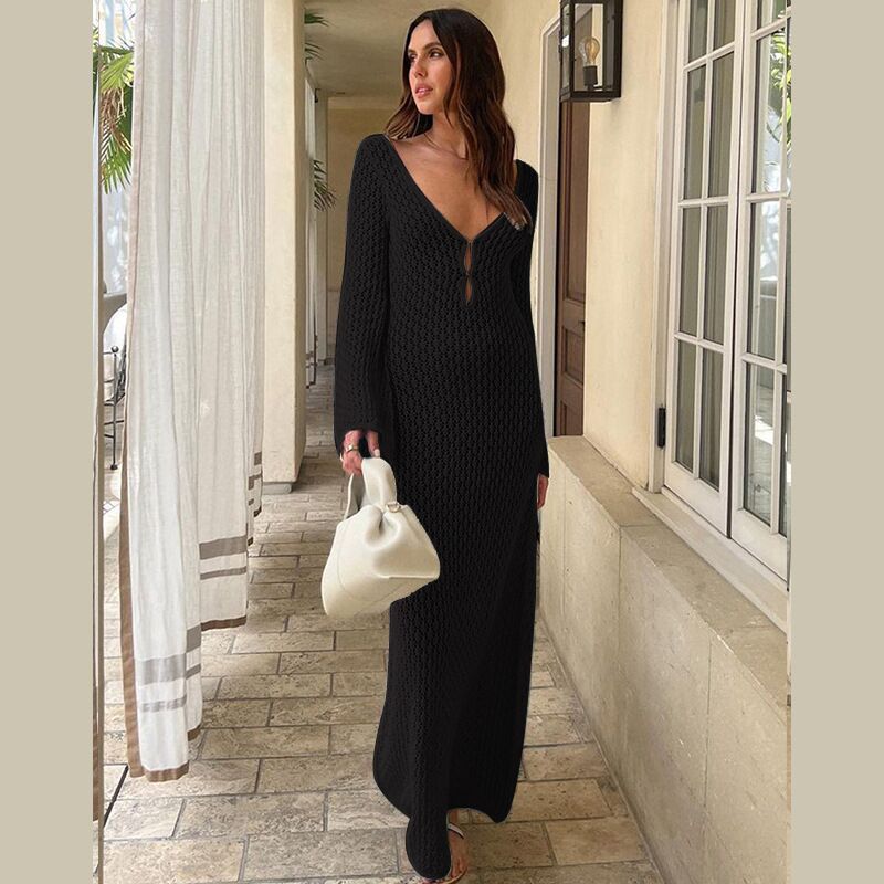 Woman in a black long crochet dress with long sleeves in an outdoor setting.