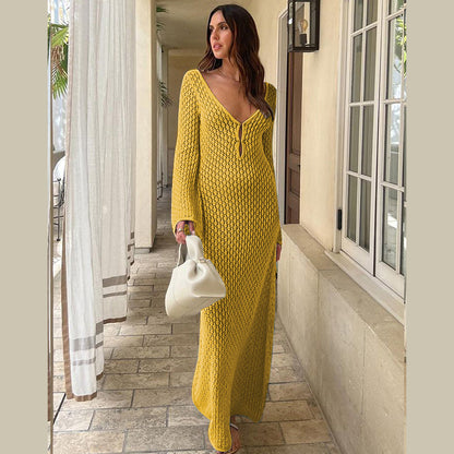 Woman in a long yellow crochet knit dress standing in an indoor setting.