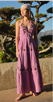 Woman in an embroidered lavender halter maxi dress standing outdoors with trees and mountains in the background