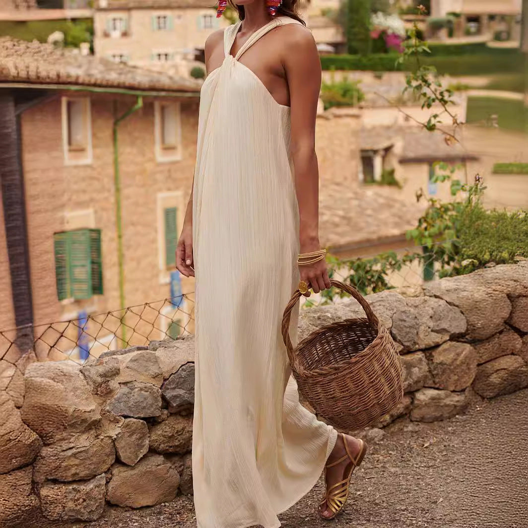 Woman in a white halter style dress walking on a stone pathway in a village.