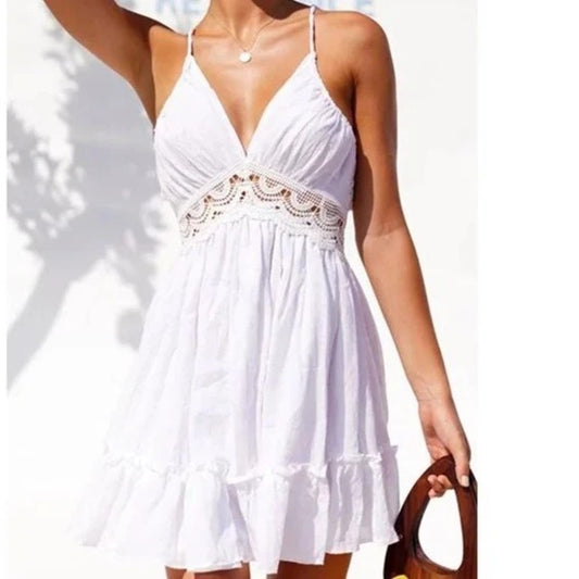 A woman wearing a short white boho lace halter dress with a V-neck, sleeveless design, and a swing skirt.