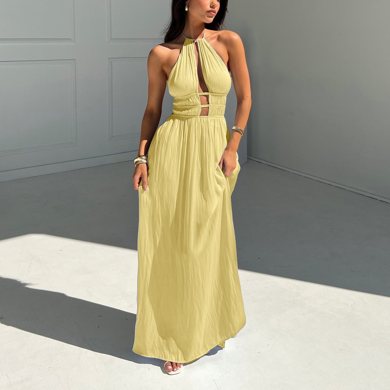 Woman wearing a yellow halter maxi dress against a gray background room