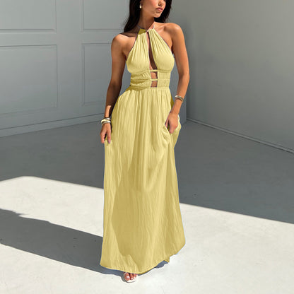 Woman wearing a yellow halter maxi dress against a gray background room